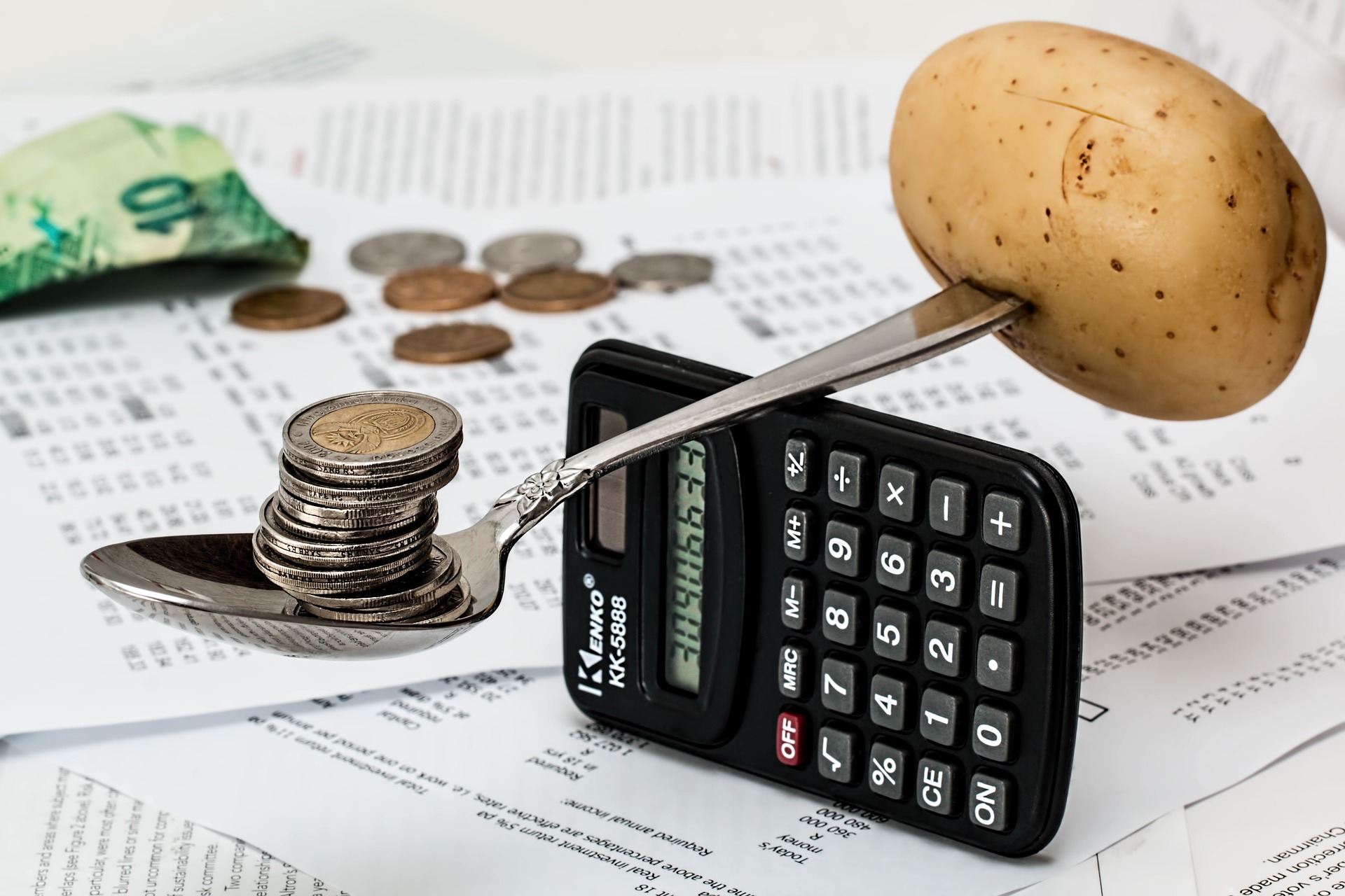 Coins and potatoes balanced on a spoon and calculator