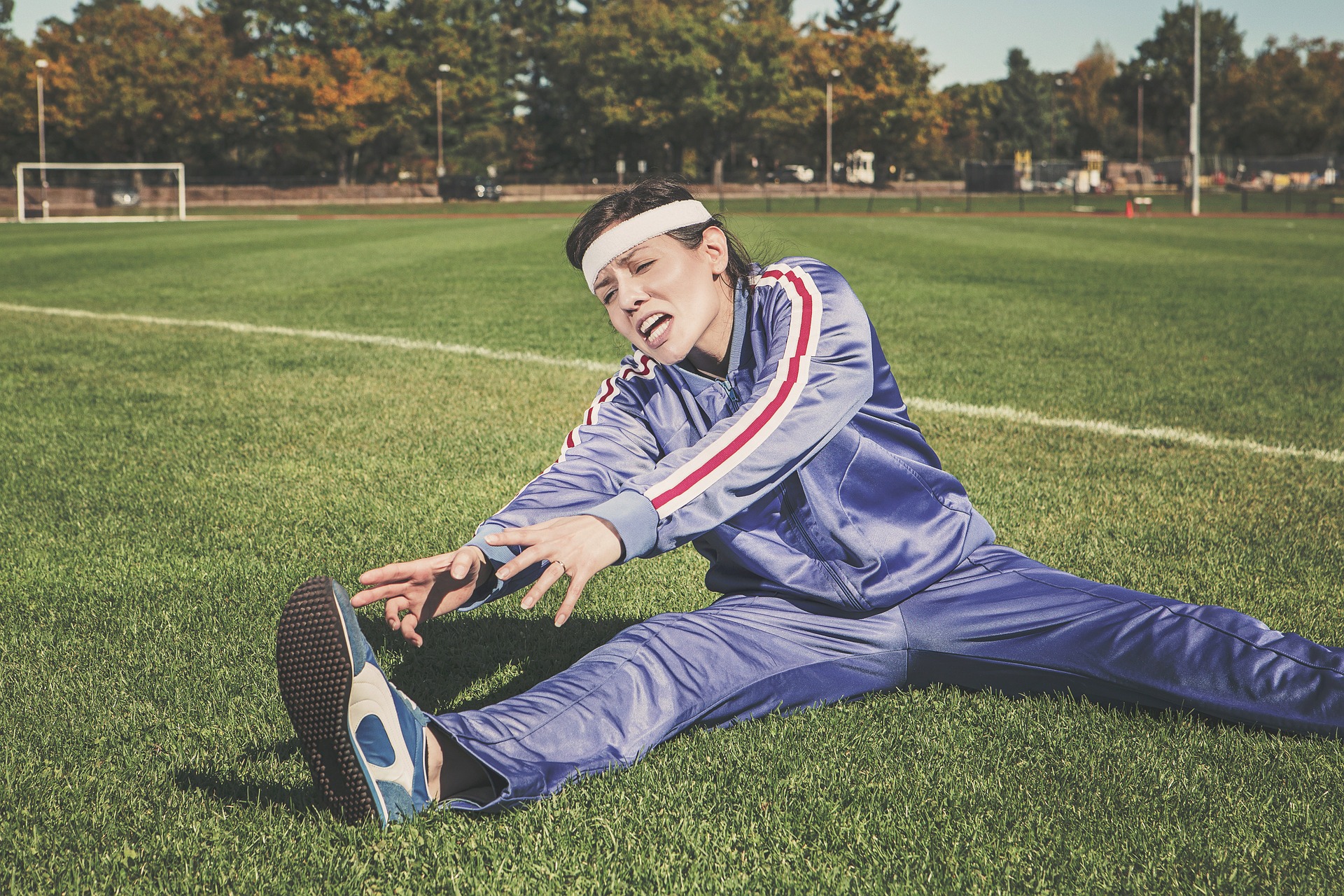 Woman stretching in trackpants on a soccer field